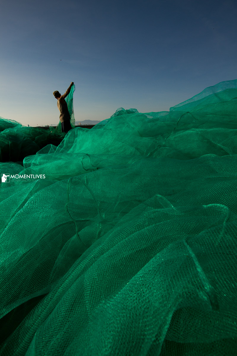 Iconic image of Nha Trang fishing life with a person working on a vast fishing net