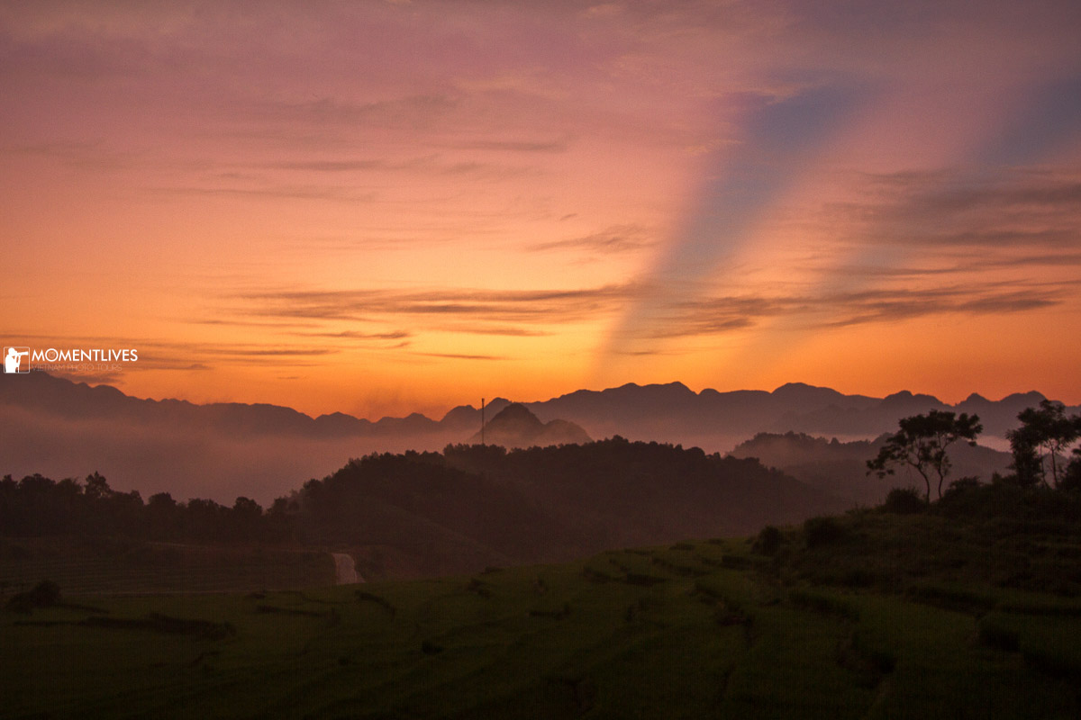 Sun rises over the mountain of Pu Luong, creating a bright orange color over the rice field