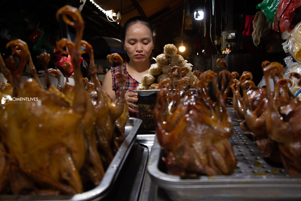 A lady selling roasted chickens on the street of Hanoi
