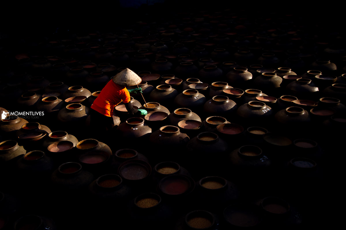 A lady stirring a soy sauce jar in the village of Ban Yen Nhan, Vietnam