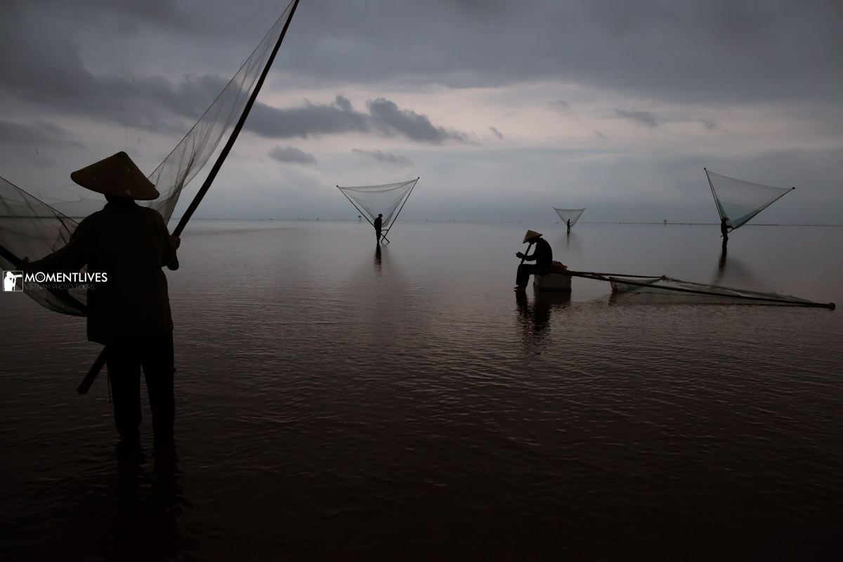 A fisherman sitting among other fishermen in the Infinite sea of Thai Binh, Vietnam