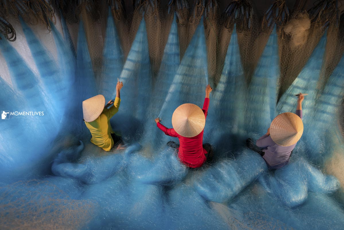 03 fishermen wearing conical hats and mending fishing net