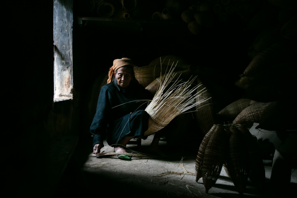 A lady sitting and weaving a fish traps in Thu Sy village