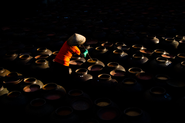 A lady stirring soy sauce in the village of Ban Yen Nhan