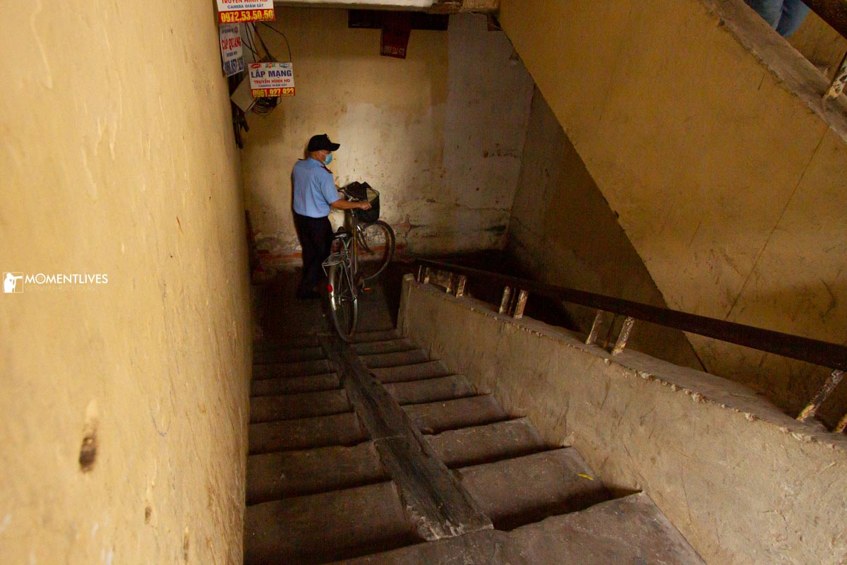 A man walking his bicycle downstairs in Hanoi