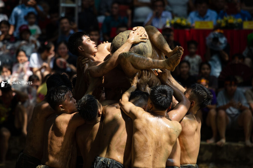 A mudball wrestling player is lifted up by his team