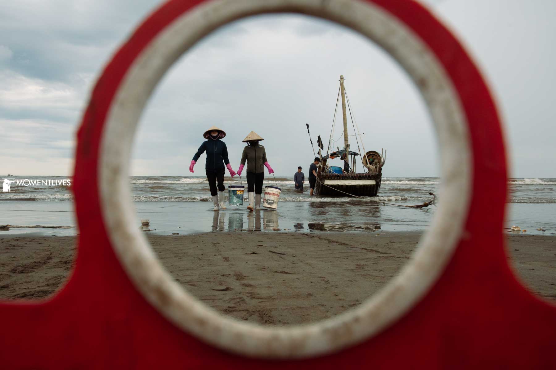 02 ladies carrying fish baskets from a boat on a beach in Nam DInh