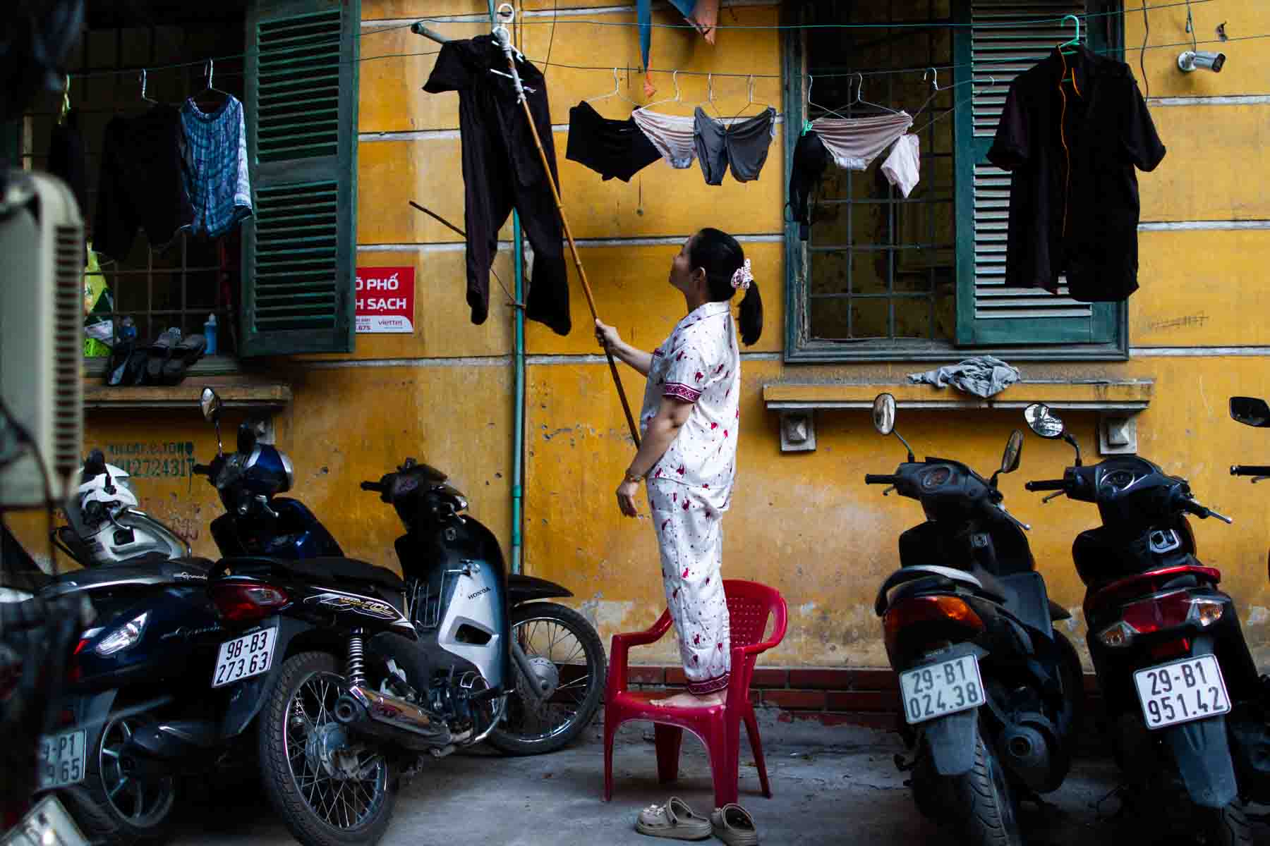 Lady drying her clothes in an alley of an old residential area in Hanoi
