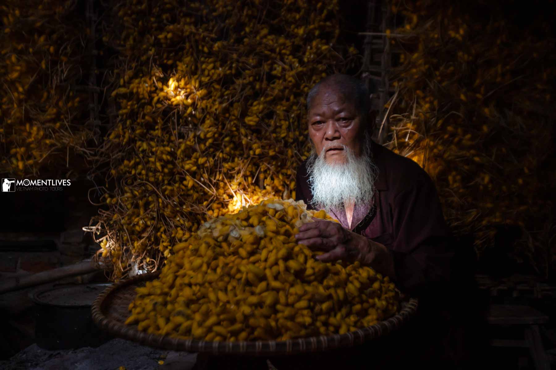 A man sitting next to a tray full of cocoons